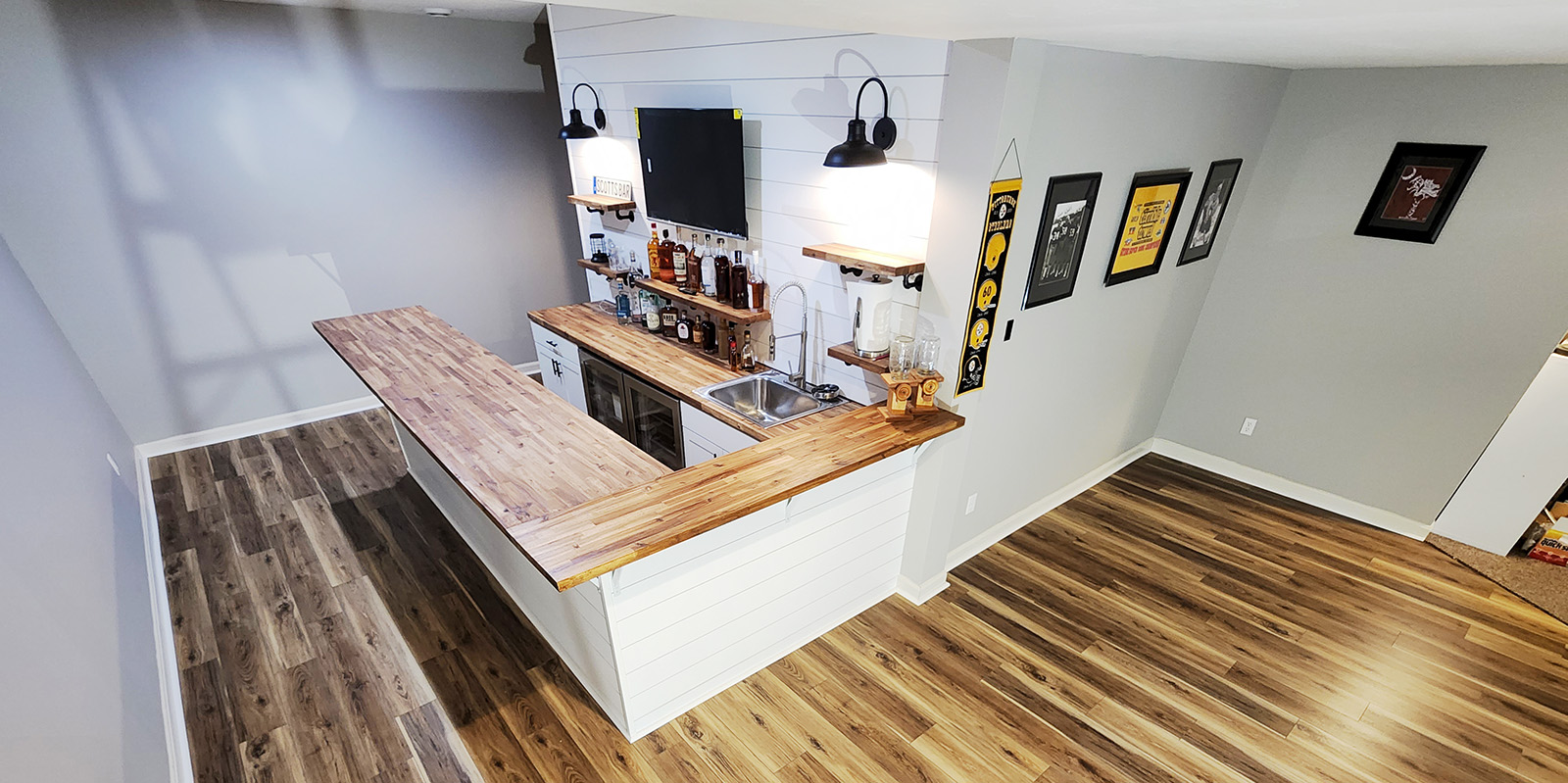 A remodeled basement with a custom bar featuring beautiful wood and Steelers decorations