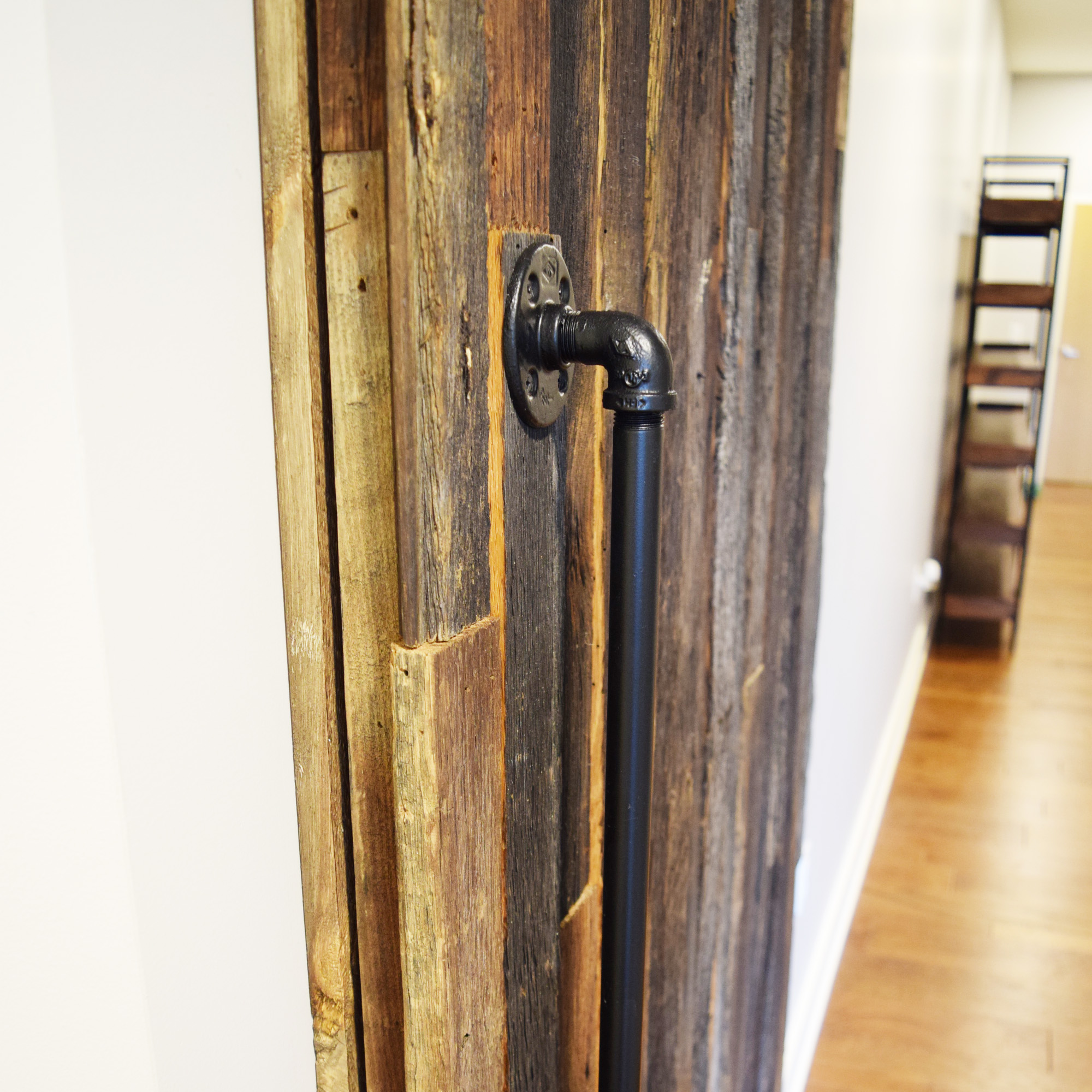 A rustic wood barn door with pipe handle installed in a home