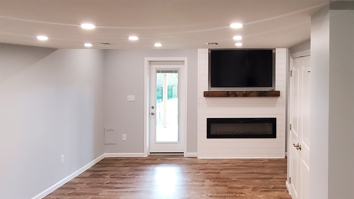 A finished basement with flooring, drywall, lighting, and a custom entertainment center