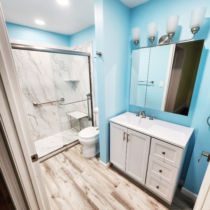 A sky blue bathroom with marbled walk-in accessible shower