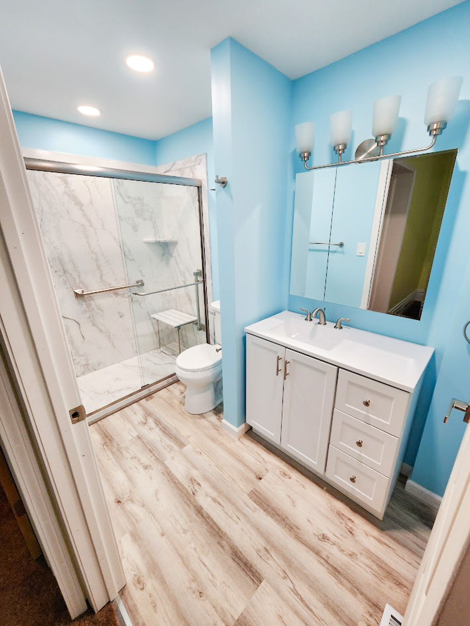 A sky blue bathroom with marbled walk-in accessible shower